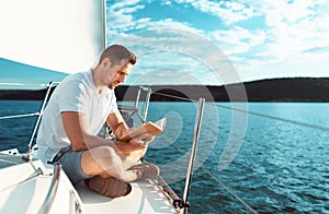 Man Reading Book Sitting On Yacht Sailing In Sea