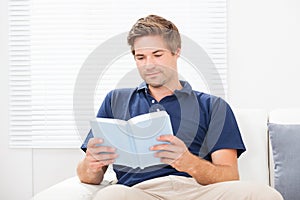 Man Reading Book On Sofa