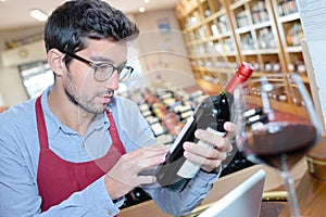 Man reading bottle wine label in wine shop