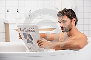 Man reading business newspaper while taking