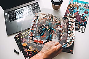 Man reading comic books on the white table in between work