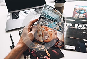 Man reading comic books on the white table in between work