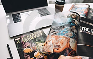 Man reading comic books on the white table in between work