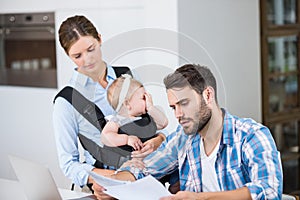 Man reading documents while wife carrying baby