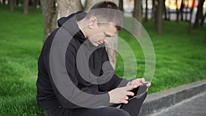 Man reading electronic book handsome guy read e-book tablet sitting public park summer day Caucasian male holding ebook