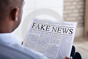 Man Reading Fake News On Newspaper