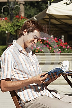 Man Reading Guidebook At Outdoor Cafe photo