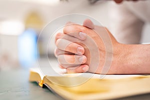 A man is reading the Holy Bible and praying in a worship room in a Christian church