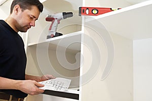 Man reading installation instruction for wardrobe.