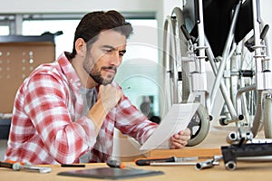 man reading instructions for assembling wheelchair in workshop