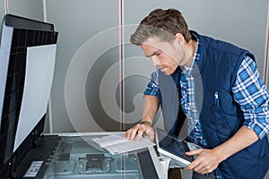 Man reading instructions to repair photocopier