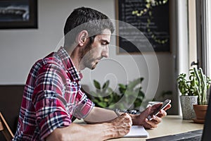 Man reading messages on phone in home office