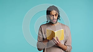 Man reading newly released hardcover book from publisher, studio background