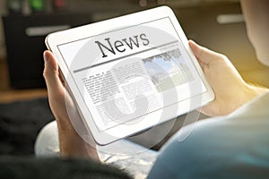 Man reading the news on tablet at home.