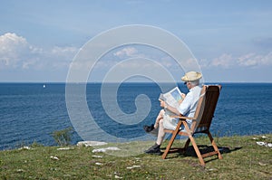 Man reading newspaper in a chair at a beautiful view