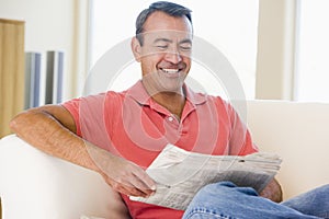 Man reading newspaper in living room smiling