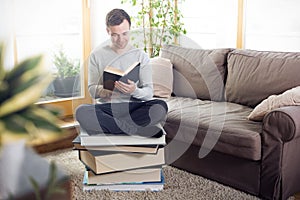 Man reading while sitting on an oversized pile of books