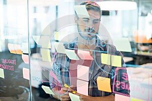 Man reading sticky notes on the glass wall