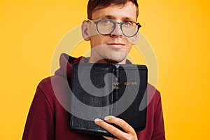 Man is reading and studying the Bible, the man is holding the Bible in his hands. Bible reading over yellow background