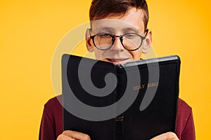 Man is reading and studying the Bible, the man is holding the Bible in his hands. Bible reading over yellow background