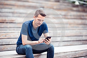 Man is reading text message on mobile phone while walking in the park