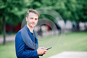 Man is reading text message on mobile phone while walking in the park