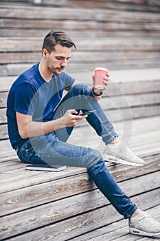 Man is reading text message on mobile phone while walking in the park