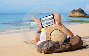 Man reading travel blog on beach