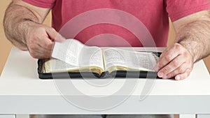 A man reads the Bible and looks for a specific place in the text.