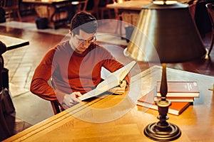 Man reads a book doing study research sitting on public library table