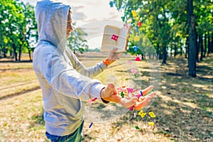 A man reads a book in the park, letters fly from above and fall on his hand, exhaustive knowledge in nature