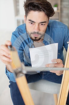 man reads letter while he repairs furniture