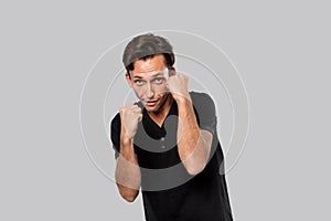 Man ready to fight standing in a boxing pose isolated over grey background.