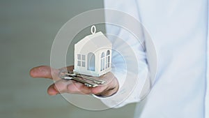 A man realtor holding white house model and house key in hand. Mortgage loan approval home loan and insurance concept
