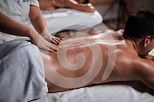 Man receiving back massage from masseur in spa