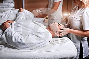 Man receiving back massage from masseur in spa