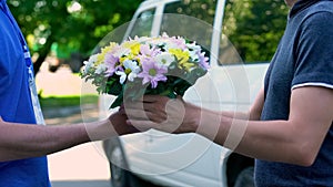 Man receiving beautiful bouquet from delivery man, order and shipment service