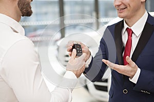 Man receiving car keys from salesman at the dealership