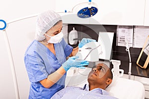 Man receiving facial light therapy in aesthetic medicine office
