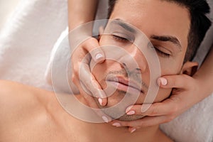 Man receiving facial massage in beauty salon