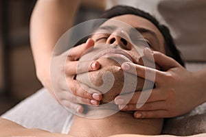 Man receiving facial massage in beauty salon, closeup