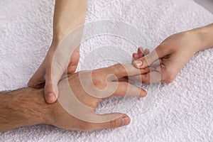Man receiving hand massage on soft towel, closeup