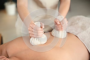 Man receiving herbal bag massage in spa salon