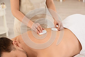 Man receiving hot stone massage in spa salon