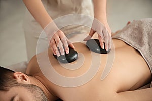 Man receiving hot stone massage in spa salon