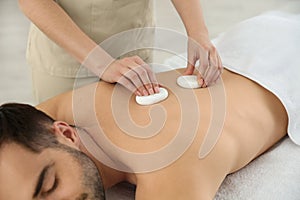 Man receiving hot stone massage in spa salon