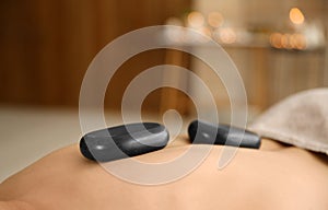 Man receiving hot stone massage in spa salon. Space for text