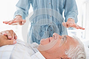 Man receiving Reiki treatment by therapist