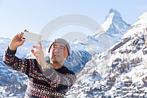 Man recording video with phone while traveling in winter Swiss Alps