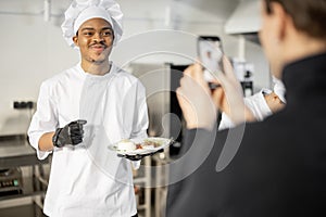 Man records on phone the process of cooking by asian chef in a professional kitchen